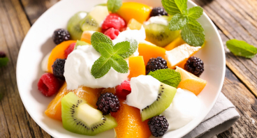 En sund og lækker frugtsalat serveret med en cremet råcreme, der giver en sød og frisk smag til den friske frugt.