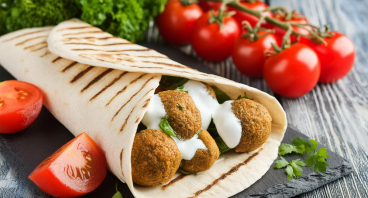 En falafel wrap er en lækker vegetarisk ret lavet med krydrede kikærteboller, friske grøntsager og cremet dressing, serveret i en blød tortillawrap.